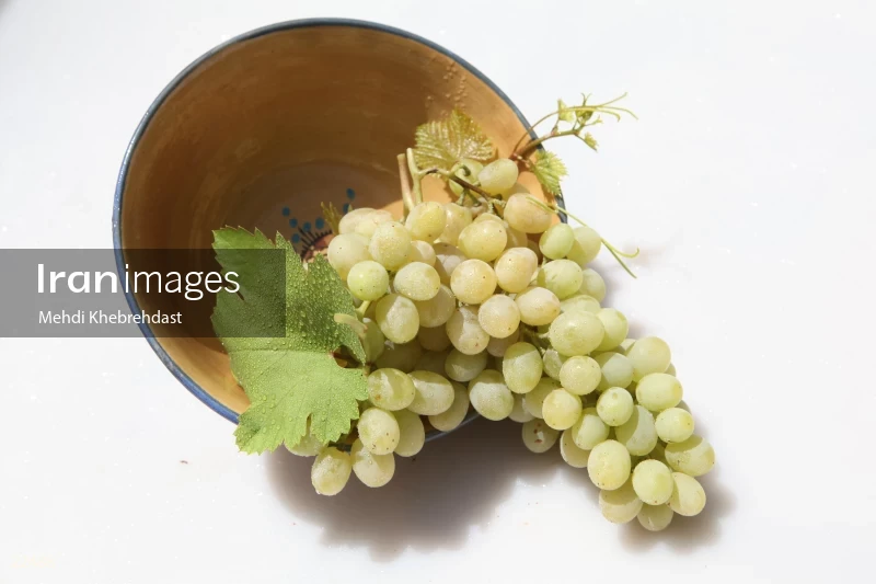 Bunch of green grapes in bowl on white background