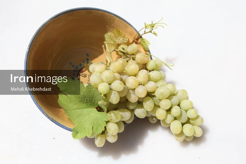 Bunch of green grapes in bowl on white background