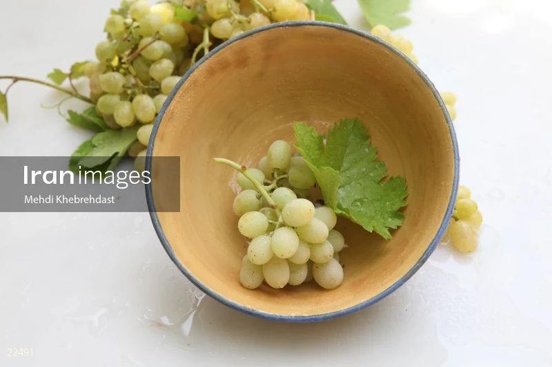 Bunch of green grapes in bowl on white background