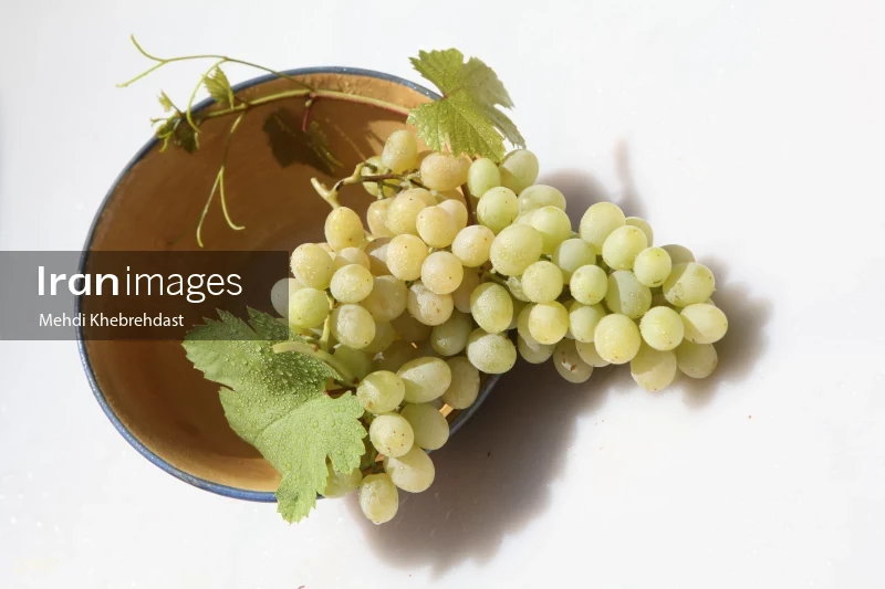 Bunch of green grapes in bowl on white background